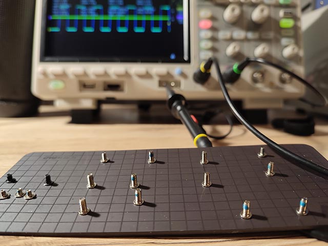 Śrubki z laptopa na tle oscyloskopu